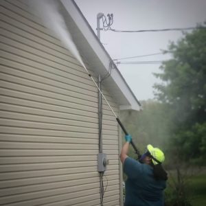 A man in an industrial suite pressure washing